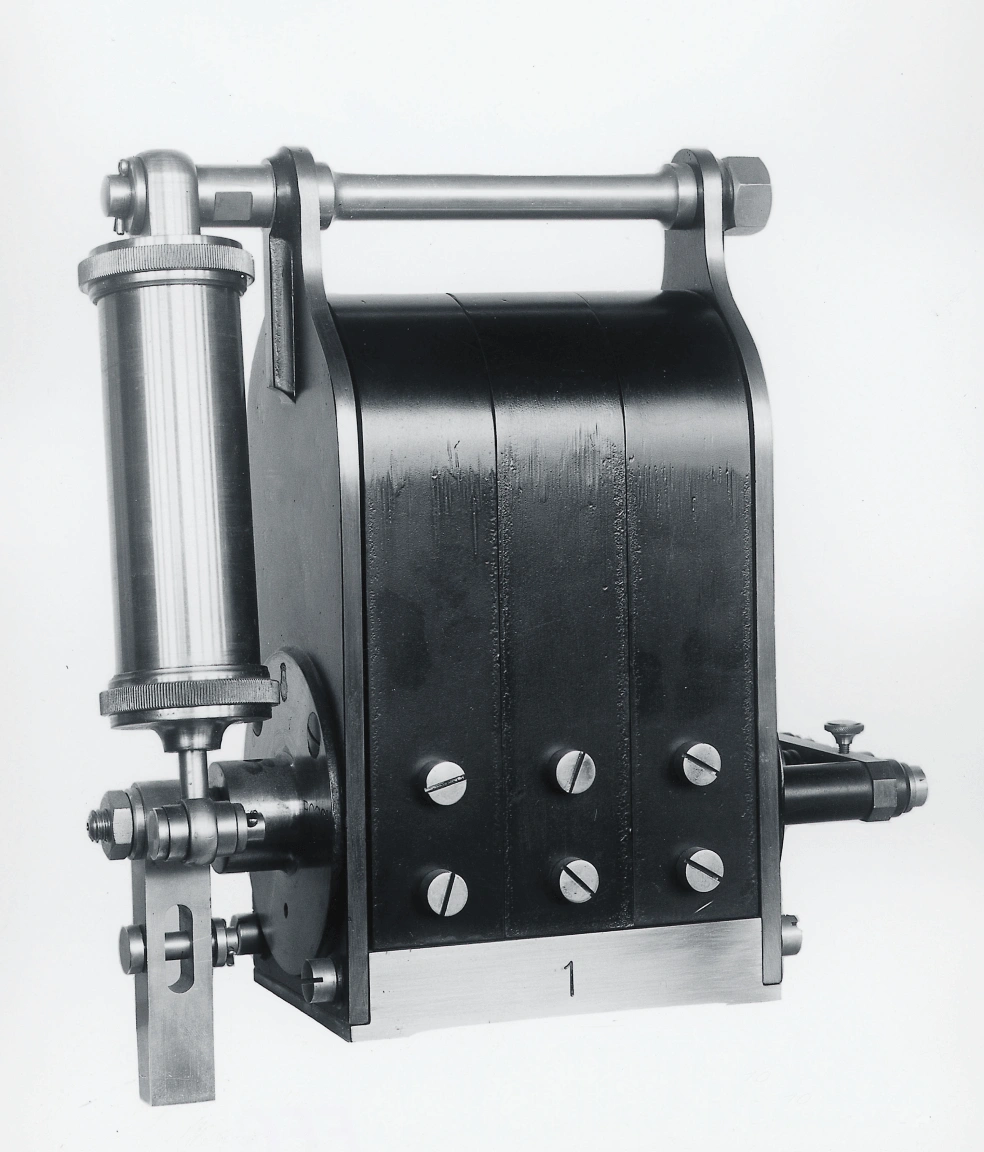 Historical black and white photograph of the first Bosch magneto ignition device from 1887 against a neutral background.